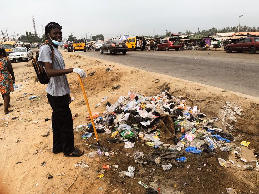 Volunteer with broom at roadside clean-up